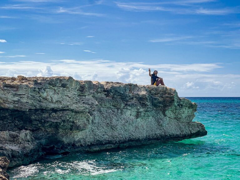a couple of people sitting on top of a cliff next to the ocean