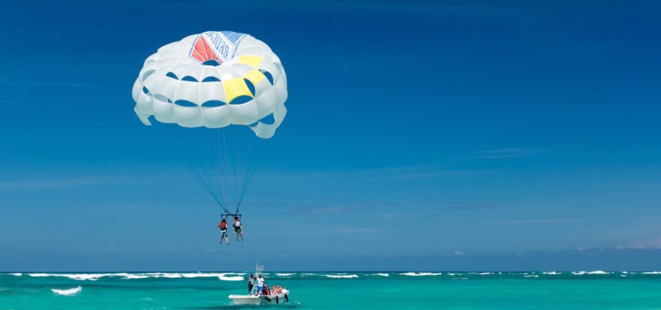 two person riding parachute near beach