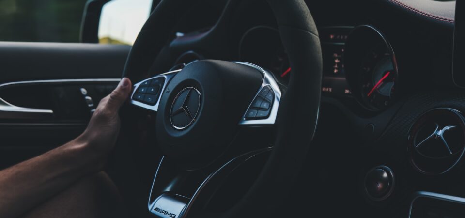 person holding on black steering wheel inside car. Car Rent in Punta Cana